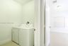 Utility area featuring neutral tile flooring, white walls, and a multi-panel interior door