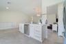 Kitchen island featuring white shaker-style cabinetry, quartz countertops, a brass faucet, and a stainless steel dishwasher, complemented by tile floo