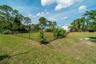 Fenced yard featuring a level lawn, mature shade trees, and perimeter landscaping
