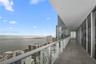 Covered balcony featuring oversized tile flooring, a glass panel railing, and full-height sliding glass door access