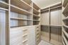 Walk-in closet featuring floor-to-ceiling wood-finish shelving, custom drawer banks, and integrated garment rods