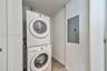 Dedicated laundry area featuring a stacked washer and dryer set and a recessed electrical service panel