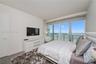 Floor-to-ceiling sliding glass doors, recessed lighting, and water-facing balcony access