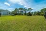 Expansive backyard featuring an open grass lawn, mature trees, and perimeter fencing
