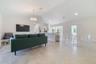 Open-concept interior featuring vaulted ceilings, oversized tile flooring, a tiered kitchen island with bar seating, and a decorative tiered chandelie