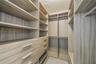 Walk-in closet featuring custom wood-finish cabinetry, built-in shelving, multiple pull-out drawers with metal hardware, and dual hanging rods