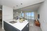 Kitchen island featuring stone countertops, a stainless steel under-mount sink, matte-finish cabinetry, and three pendant light fixtures, with expansi