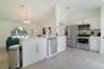 Kitchen featuring white shaker cabinetry, stainless steel appliances, large-format tile flooring, a breakfast bar, and a vaulted ceiling with a circul