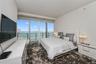 Floor-to-ceiling windows, private balcony access, recessed lighting, and water scenery