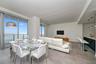 Open-concept living space featuring floor-to-ceiling glass doors, stone-finish tile flooring, recessed ceiling lighting, and a kitchen island with a s