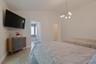 Vaulted ceilings, large-format tile flooring, and a contemporary multi-arm brass chandelier