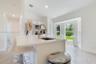 Kitchen featuring a central island with a quartz countertop, an undermount sink with a gold-finish gooseneck faucet, tile flooring, and a bay window
