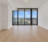 Floor-to-ceiling windows with black frames, wood-finish flooring, and a glass-railing balcony