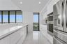 Kitchen featuring white gloss cabinetry, expansive solid-surface countertops, stainless steel double wall ovens, high-gloss tile flooring, and floor-t