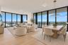 Floor-to-ceiling windows, wood-finish flooring, recessed lighting, and a circular metal-frame pendant light fixture