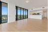 Open-concept living space featuring floor-to-ceiling windows with dark frames, wood-finish flooring, and a kitchen equipped with white flat-panel cabi