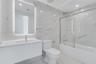 Bathroom featuring large-format stone-patterned wall and floor tile, a modern floating vanity with an integrated sink, a frameless glass tub enclosure