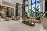 Double-height floor-to-ceiling windows, polished stone flooring, recessed ceiling lighting, reflective wall paneling, and architectural metallic accen