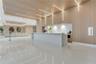 Modern lobby featuring high-gloss tile flooring, floor-to-ceiling wood-finish wall paneling, linear recessed lighting, and a stone-topped reception de