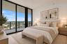 Floor-to-ceiling black-framed glass sliding doors, private balcony, wood-finish flooring, and expansive natural light
