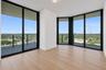 Floor-to-ceiling windows with black metal frames, wood-finish flooring, and expansive wrap-around balcony access