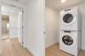 Stacked front-loading washer and dryer, wood-finish flooring, and recessed ceiling lighting