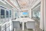 Exposed industrial ceiling with ductwork, expansive glass wall partitions, polished concrete flooring, multiple crystal chandeliers, and exterior glas