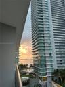 High-rise balcony featuring glass railings and panoramic water, skyline, and sunset scenery