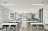 Expansive room featuring polished concrete flooring, recessed linear lighting, integrated ceiling speakers, floor-to-ceiling windows, and glass partit