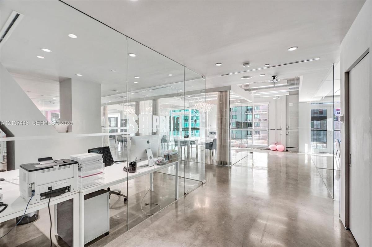 Expansive interior featuring polished concrete flooring, floor-to-ceiling glass wall partitions, and recessed ceiling lighting