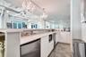 Kitchen area featuring white cabinetry, solid-surface countertops, industrial-style exposed ductwork, polished concrete flooring, and crystal chandeli