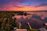 An incredible aerial perspective showcases the property's waterfront setting, private dock, and sweeping views across the water. With vibrant sunrise 