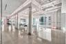 Industrial interior featuring polished concrete flooring, exposed overhead ductwork, floor-to-ceiling glass panel walls, and linear recessed lighting