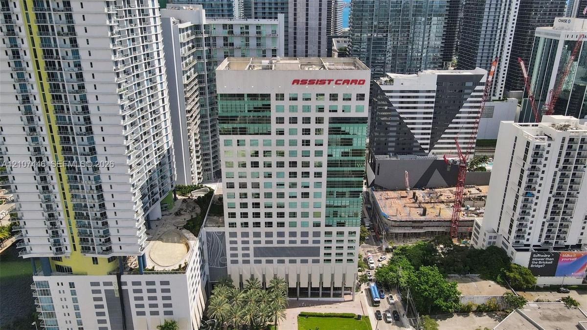 High-rise commercial building featuring a multi-story glass curtain wall, reinforced concrete facade, ground-level professional landscaping, and palm-