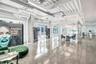 Industrial-style interior featuring polished concrete flooring, exposed overhead ductwork, soaring ceilings with steel beams, and floor-to-ceiling gla
