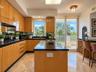 Kitchen featuring flat-panel wood cabinetry, black countertops, central island, stone-finish flooring, and built-in wine storage