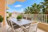 Covered balcony featuring neutral floor tile, stucco wall finishes, and a white vertical-bar railing