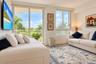 Living area featuring floor-to-ceiling glass sliding doors, horizontal windows, light-toned wall-to-wall flooring, and a private balcony with metal ra