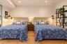 Bedroom featuring wood-finish flooring, recessed ceiling lighting, and dual wall-mounted adjustable reading lamps
