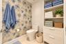 Botanical-patterned wallpaper, dual-piece toilet, and built-in floor-to-ceiling cabinetry featuring open shelving and two storage drawers