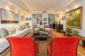 Living space featuring recessed lighting, multi-layered crown molding, mirror-paneled accent walls, and wood-finish flooring