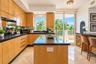 Kitchen featuring flat-panel wood cabinetry, dark stone countertops, a center island, built-in wine storage, and polished stone flooring
