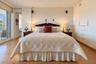 Wood-finish flooring, floor-to-ceiling built-in white cabinetry, and sliding glass doors leading to an exterior balcony