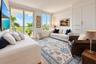 Living area featuring floor-to-ceiling windows, sliding glass door access to an exterior balcony, built-in floor-to-ceiling cabinetry, and light-toned