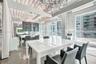 Industrial-style interior featuring exposed corrugated metal ceiling, expansive glass curtain walls, polished concrete flooring, and oversized crystal