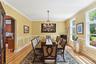 Dining space with light wood finished floors, arched walkways, crown molding, a chandelier, and a decorative wall