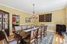 Dining space featuring arched walkways, crown molding, wood finished floors, a chandelier, and a wainscoted wall