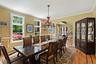 Dining space with arched walkways, light wood finished floors, crown molding, stairway, and wainscoting