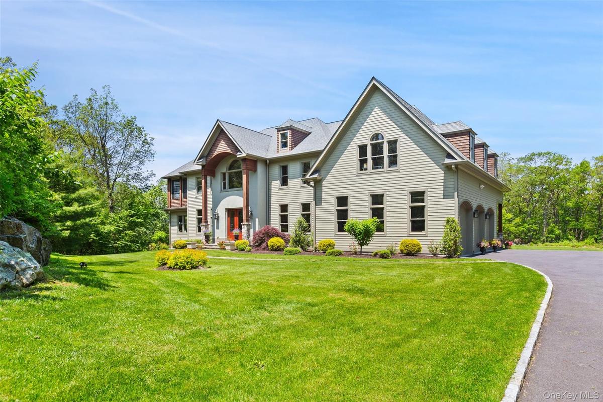 View of front of home with a garage, Belgium Block lined driveway, and a front lawn