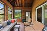 Sunroom / solarium with wood ceiling, wooden walls, a wood stove, and hardwood / wood-style floors